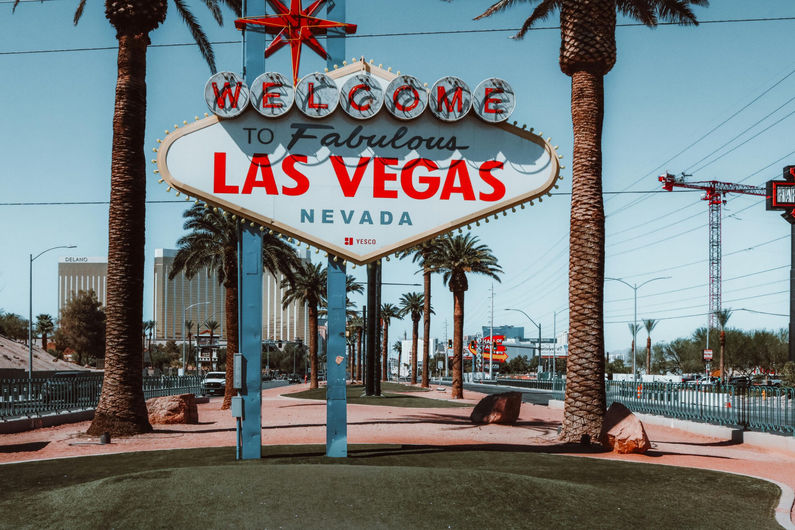 The famous "Welcome to Las Vegas" sign with palm trees in daylight.